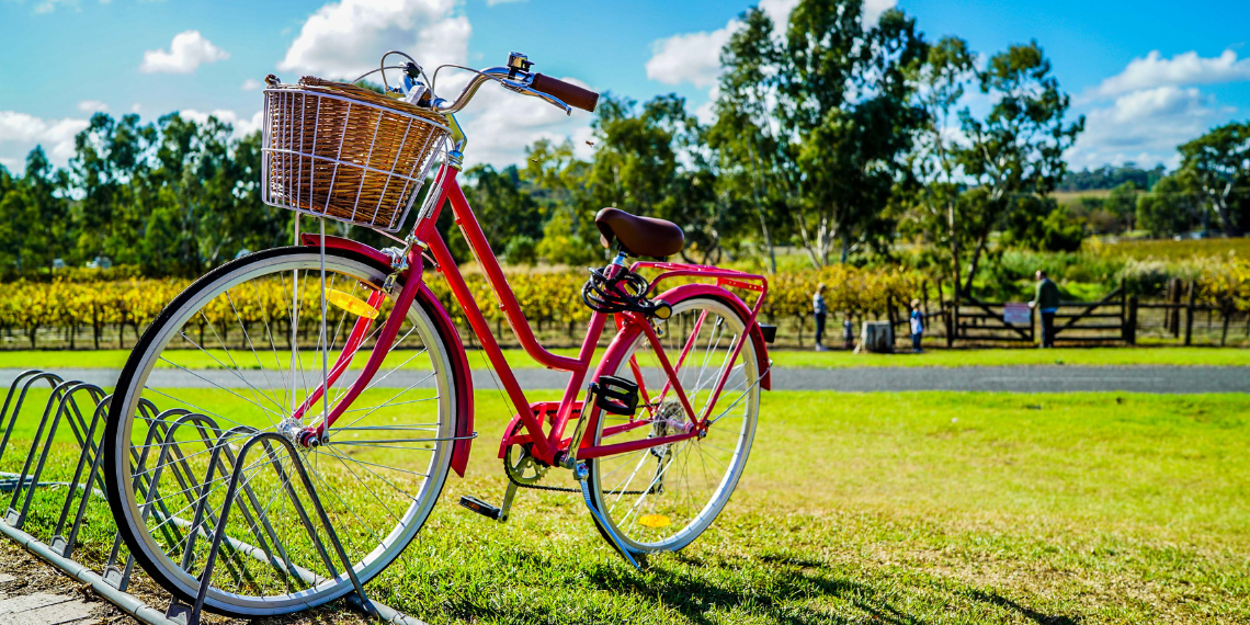 A vibrant red bicycle parked in a bike rack amid the lush greenery of a serene park, waiting for its next adventure.