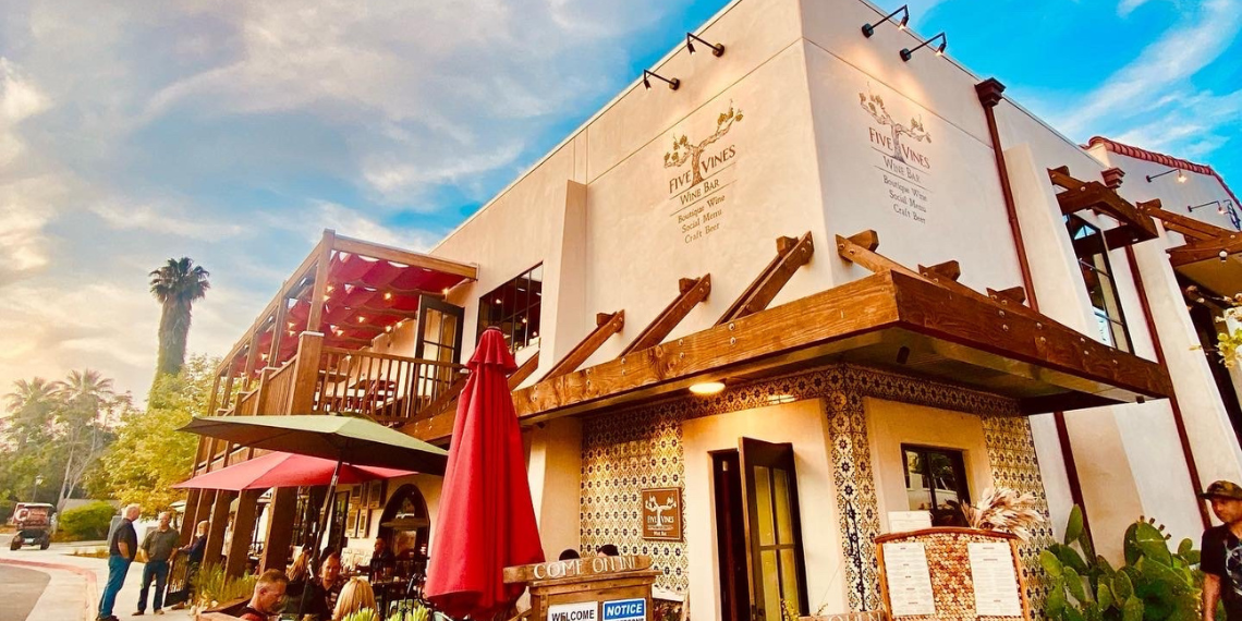 The exterior of Five Vines Wine Bar bathed in the warm glow of the setting sun, creating a serene atmosphere for wine enthusiasts to gather and enjoy a relaxing evening amidst charming surroundings.