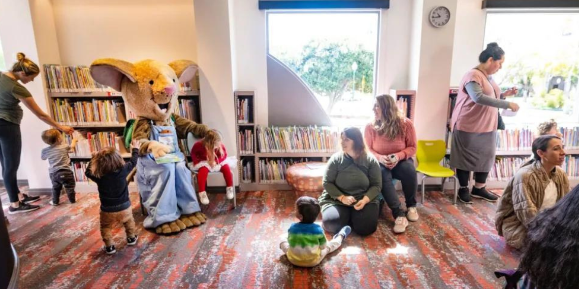 Children gather for storytime at San Juan Capistrano Library, sitting attentively as a librarian reads aloud from a colorful storybook.