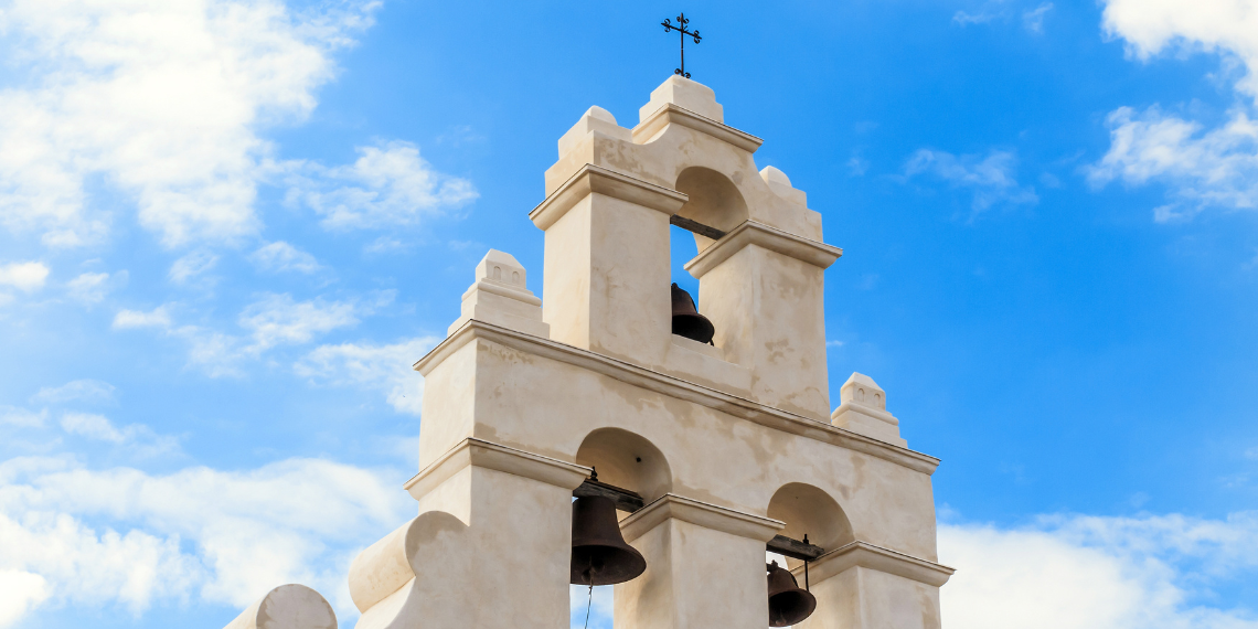 Iconic mission bells set against a clear Southern California sky, epitomizing the town's historical charm and spiritual heritage.