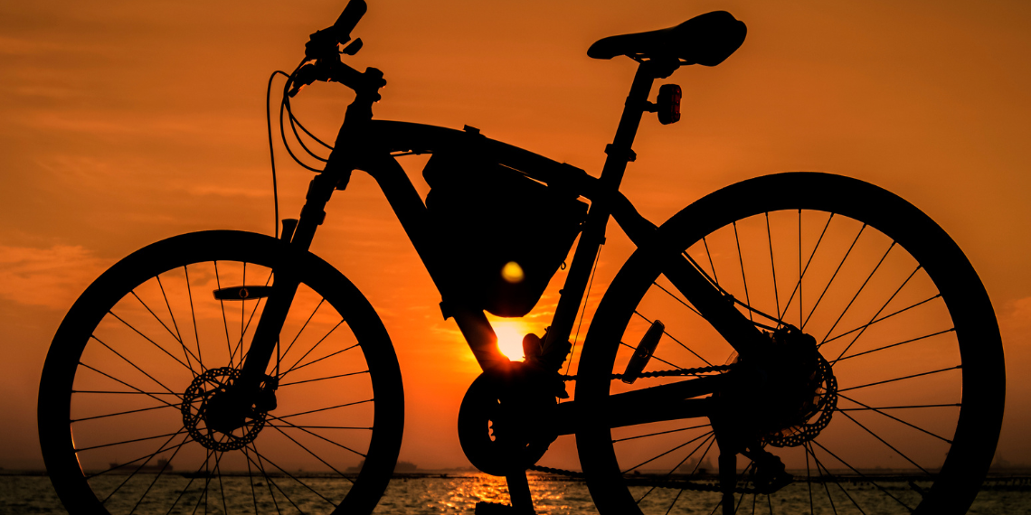 A bicycle silhouetted against an orange sky, symbolizing the conclusion of a rewarding bike ride at sunset.
