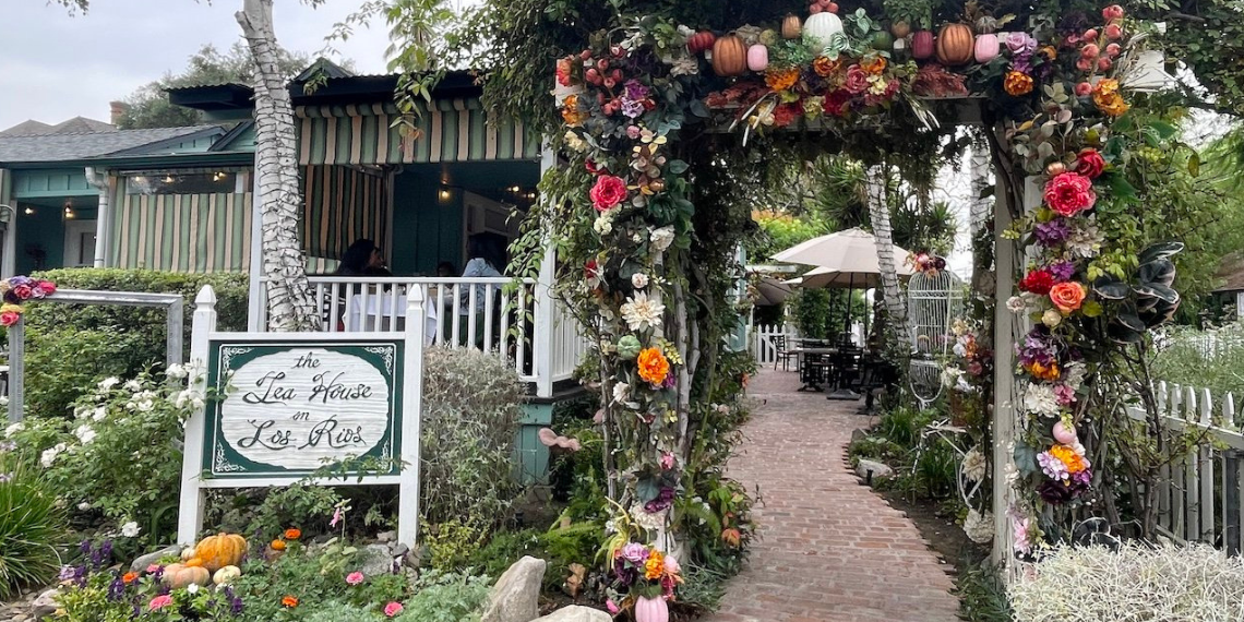 The Tea House on Los Rios, adorned with a blooming archway covered in vibrant flowers, creating a picturesque and inviting entrance to the charming establishment.