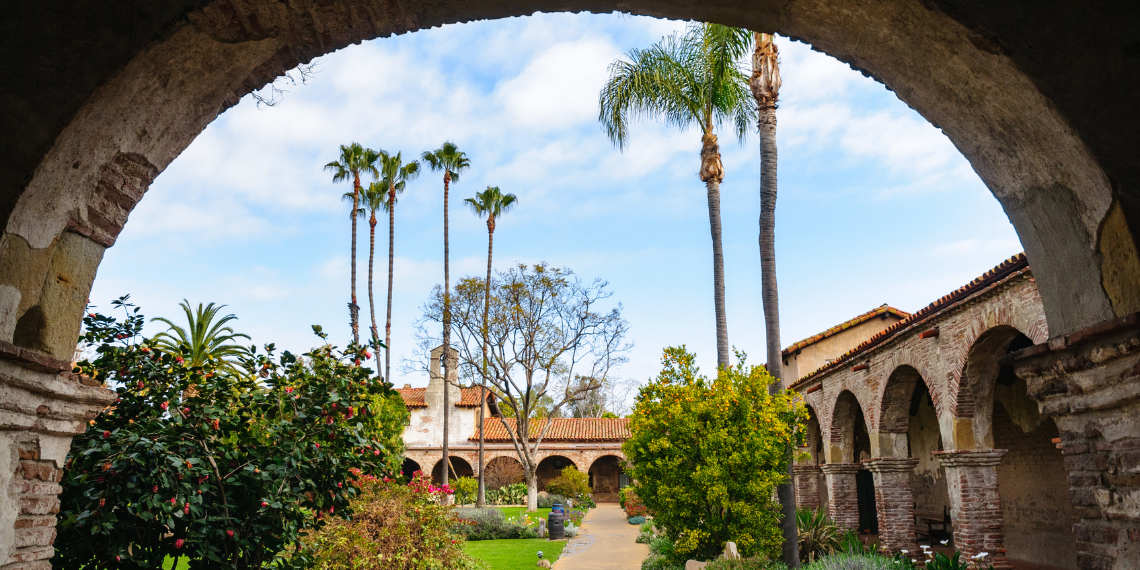 San Juan Mission's lush garden framed by an archway, offering a serene and inviting glimpse into the historic beauty of the mission grounds.