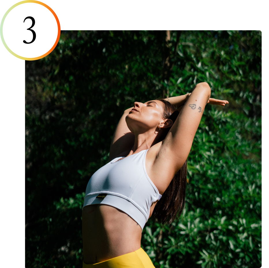 Woman stretching outdoors in white sports bra and yellow leggings.