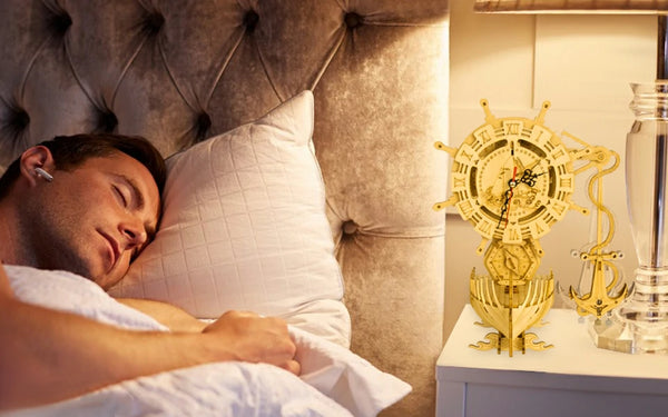 a man sleeping in bed with a ship clock model on bedside