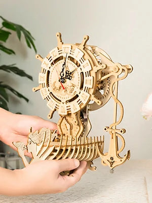 two hands holding a ship clock model
