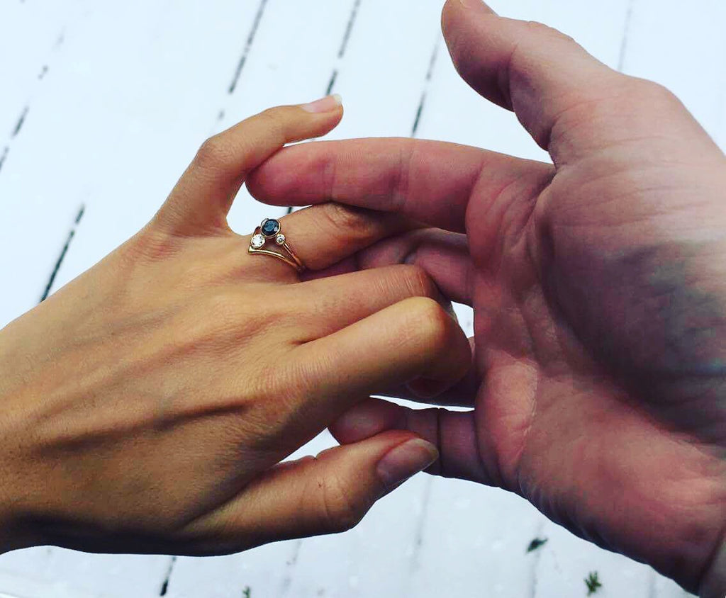 Handmade engagement ring with dual diamonds being placed on a woman's finger, capturing a special moment by What If You Stayed in Montreal.