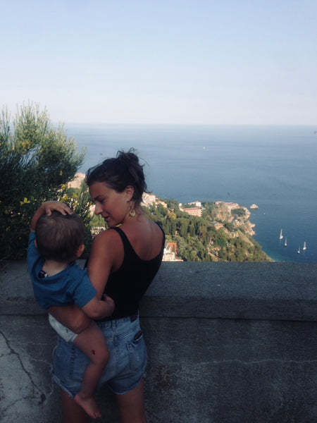 Young Mother Holding Her Baby On her Hips While Looking Over The Mediterranean On a Beautiful Sunny Day