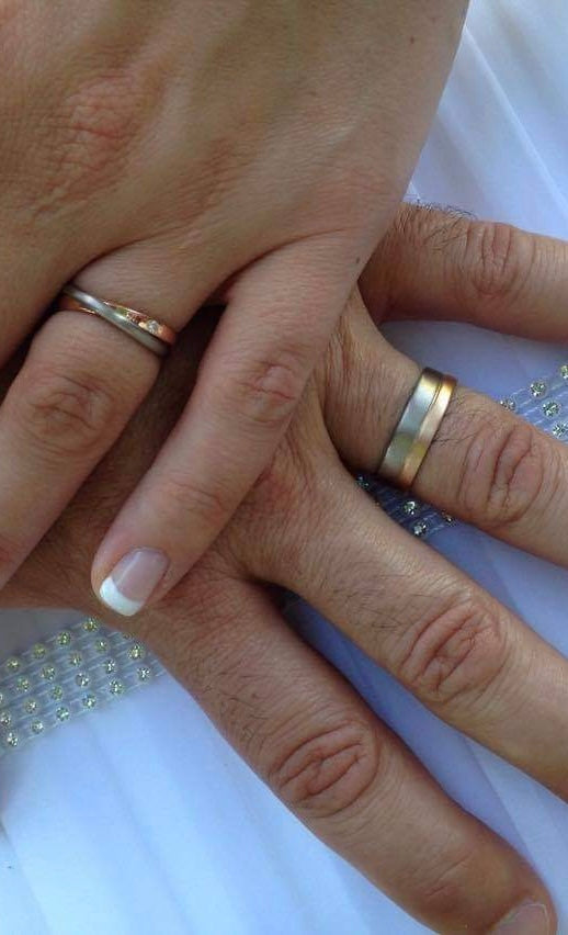 Close-up of a couple's hands intertwined, displaying their wedding bands in 14k gold and white gold, crafted by What If You Stayed in Montreal