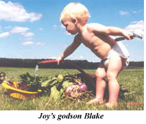 Joy's 1 yr old godson, Blake, stands wearing just a diaper in a field next to several harvest baskets - Renee's Garden