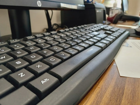 black HP brand keyboard and dsktop on a brown wooden desk office
