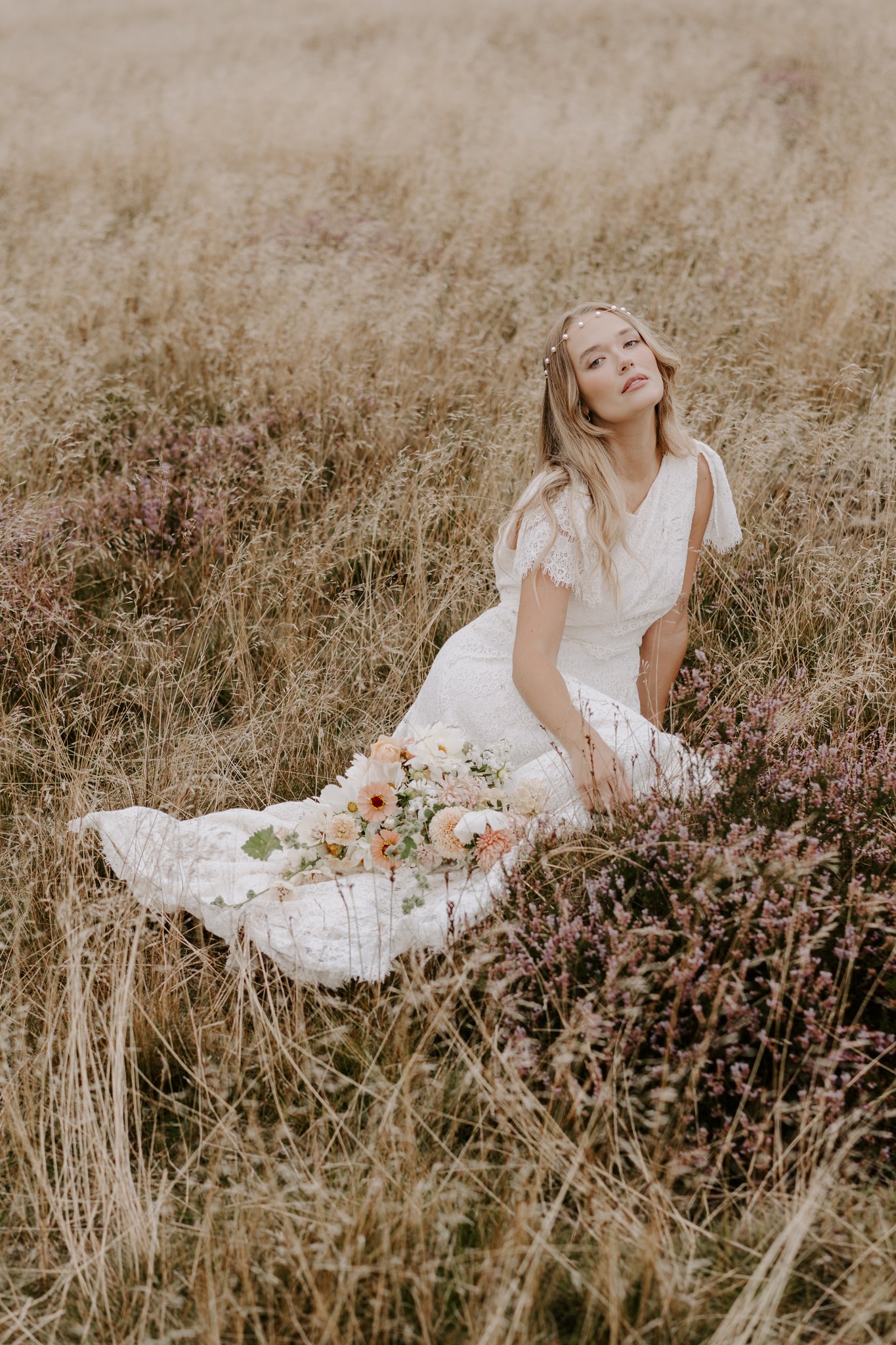 Bride sitting in the heather with a long flowing dress and pearl forehead band