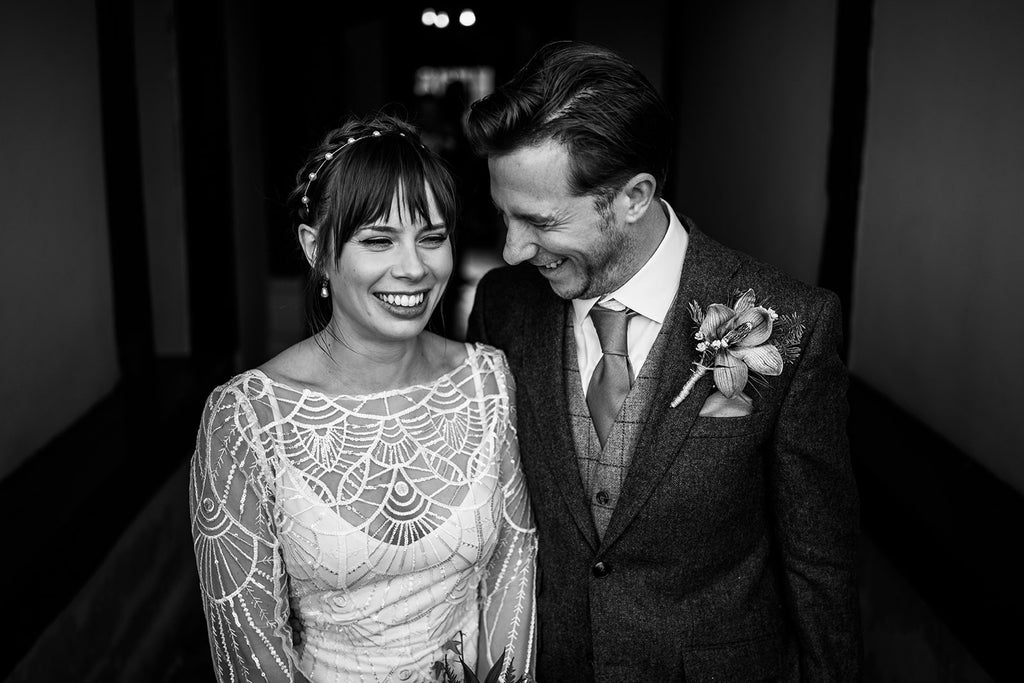 Bride and groom laugh together at their modern elegant rustic winter wedding