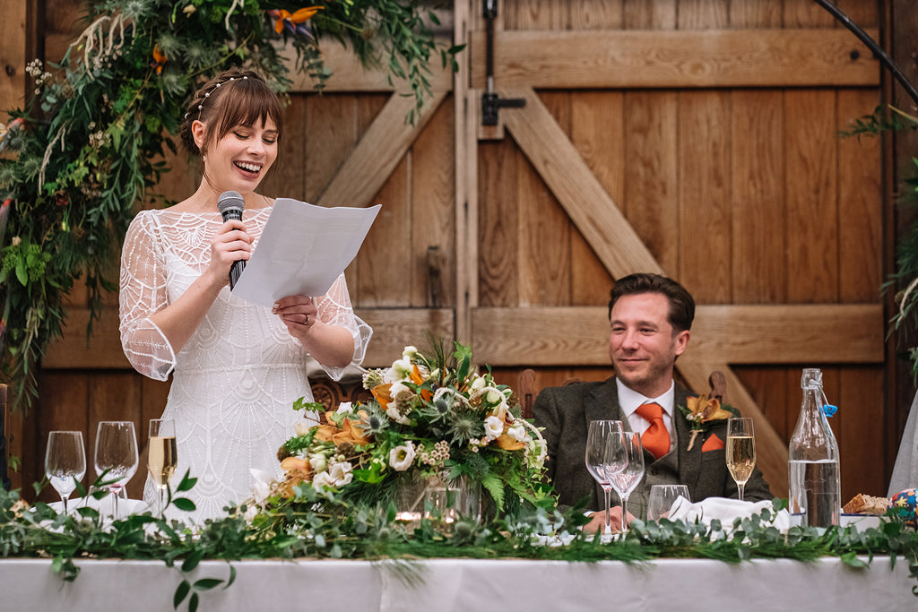 bride wearing a simple pearl headband at a wedding gives a speech