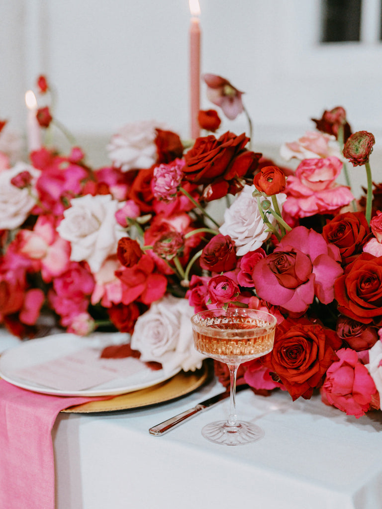 pink and red wedding tablescape for a modern romantic wedding with a bride in a satin hair bow