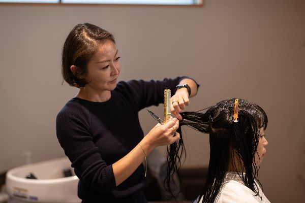 A woman having her hair cut by a hairdresser at a beauty salon. | Mane Addicts