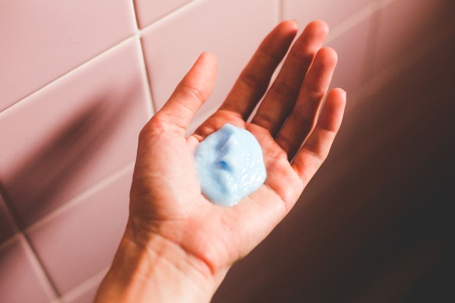 Person holding conditioner for oily hair in the palm of their hand