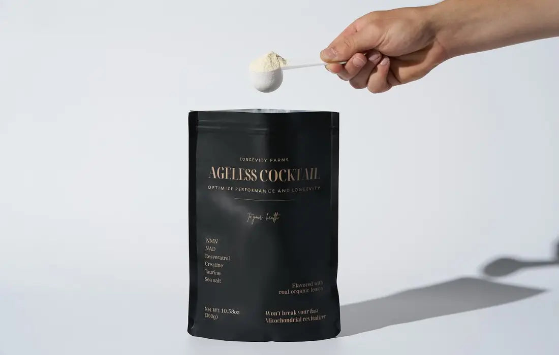 Anti-aging supplement Ageless Cocktail shown with a scoop of powder above its sleek black packaging.