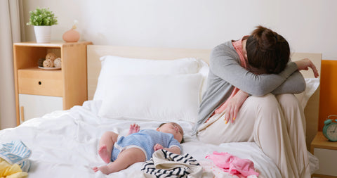 Exhausted mother with her baby on a bed