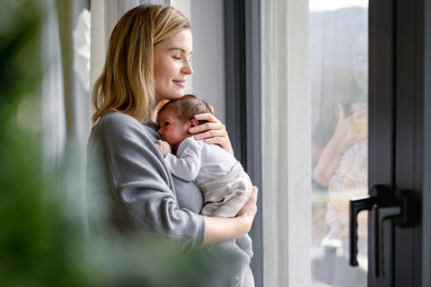 Image of a contented mother and newborn with the mother gazing outside