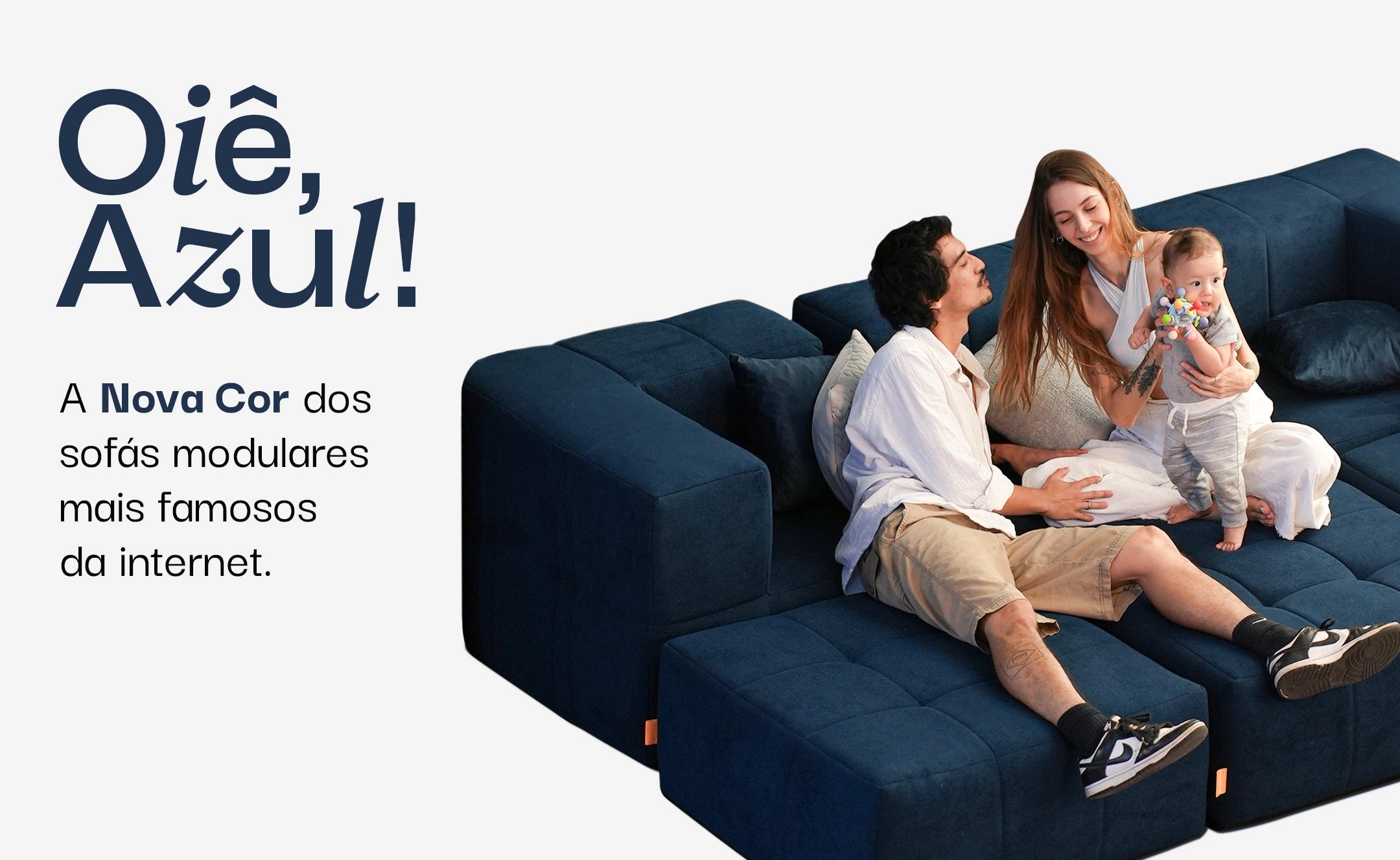Banner de divulgação do novo sofá na cor azul, onde tem um casal sentado em cima do sofá, com uma criança no colo
