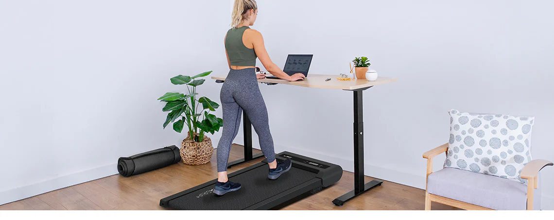 Woman working on her laptop while walking on the LSG Steps A1 Walking Pad Under Desk Treadmill in her living room