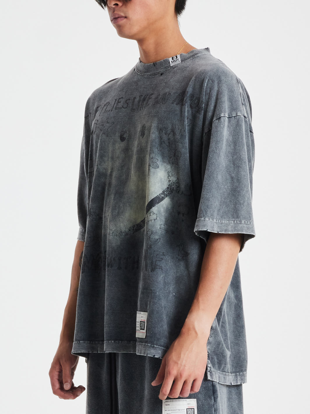 Person wearing a MAISON MIHARA YASUHIRO Bleached Tee with a smiley face and text, paired with matching shorts.