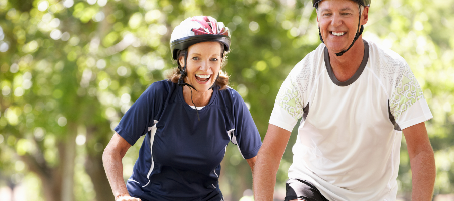 couple laughing and cycling together outdoors amongst the trees