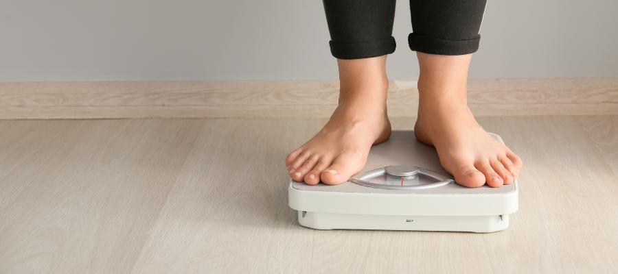 white woman wearing black leggings stood on some weighing scales