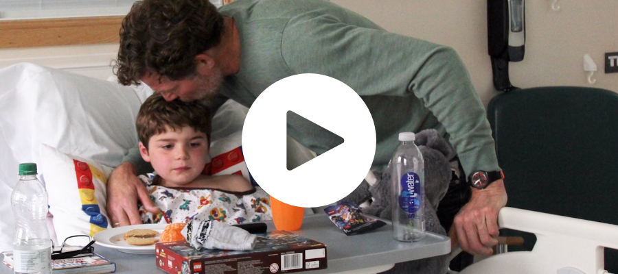 young boy in hospital being kissed by his father, he has muscular dystrophy