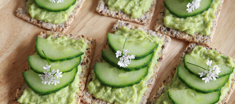 wholegrain crackers topped with cucumber and avocado and small white flowers