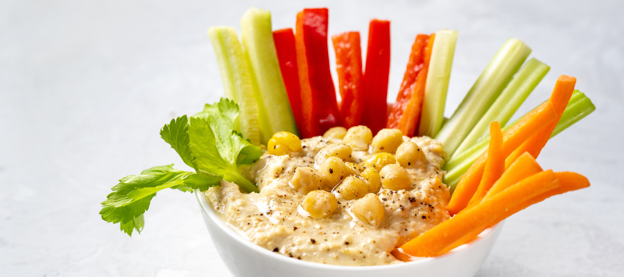 small bowl of hummus with cut up veggies, carrots, peppers, and celery