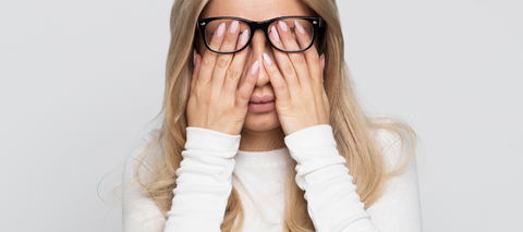 women with blonde hair covering face with tiredness wearing white shirt