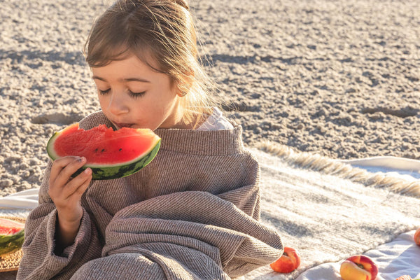a girl eating watermelon at a beach