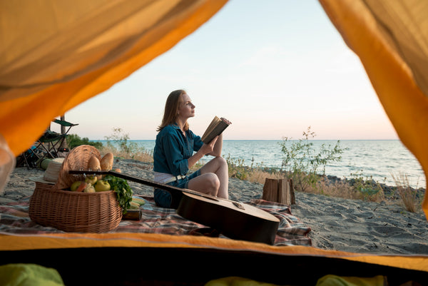a woman camping reading book at the beach