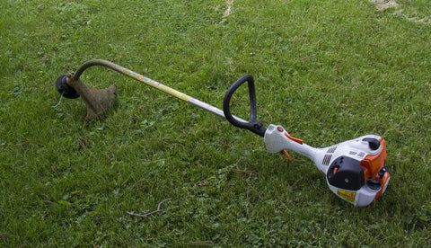 Gasoline Powered String Trimmer laying on the cut lawn
