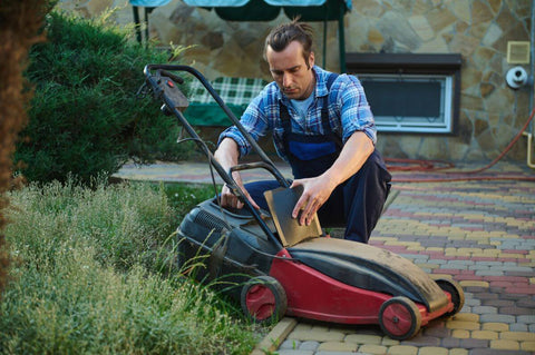 hispanic gardener in blue work uniform taking the cut grass