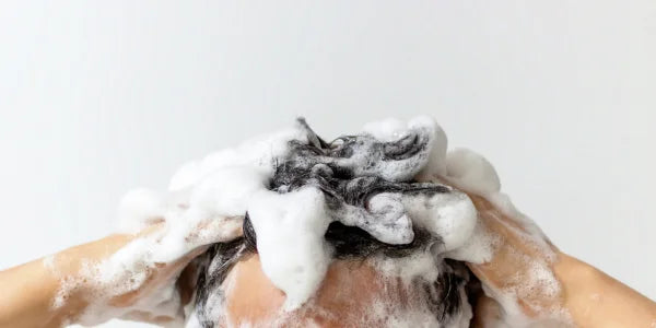 El hombre se lava el cabello con champú con cafeína