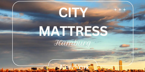 Distant view of Downtown Buffalo at sunset with fluffy clouds, 'City Mattress Hamburg, NY' caption.