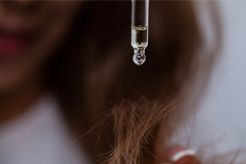 Person using a dropper to put avocado oil on hair