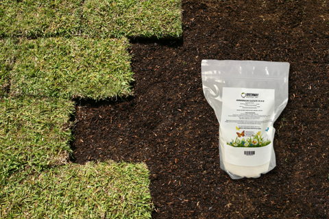 Clear bag of greenway biotech ammonium sulfate fertilizer on a bed of soil with rows of grass