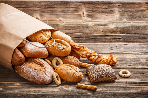 Baked bread rolls in brown paper bag on wooden table