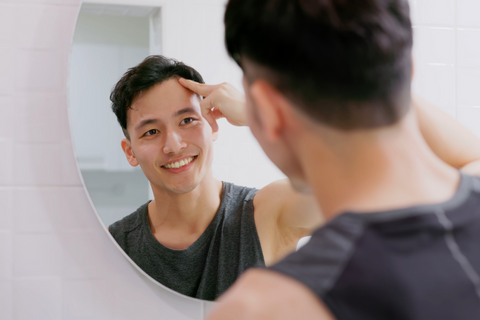 Man with short hair wearing black muscle shirt smiling in mirror