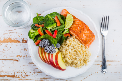 Salmon, salad, fruit and rice in small portions on white plate