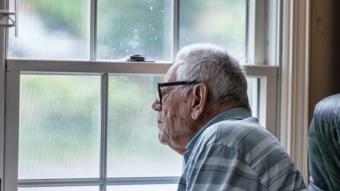 senior man with dementia staring out window