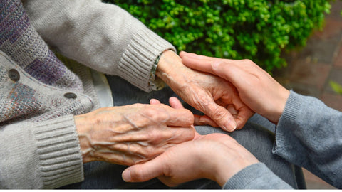 young person holding hands with senior with dementia