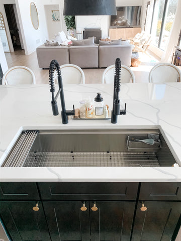 Dual matte black faucets with stainless steel workstation sink in white quartz kitchen island 