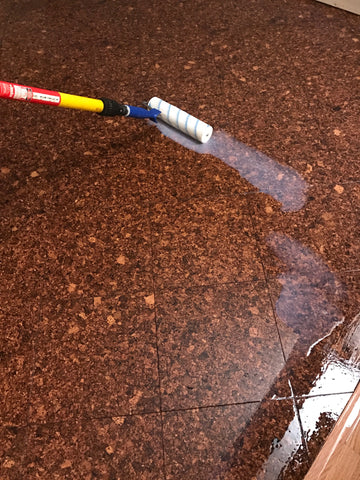 Water-based polyurethane finish being rolled onto glue down cork flooring