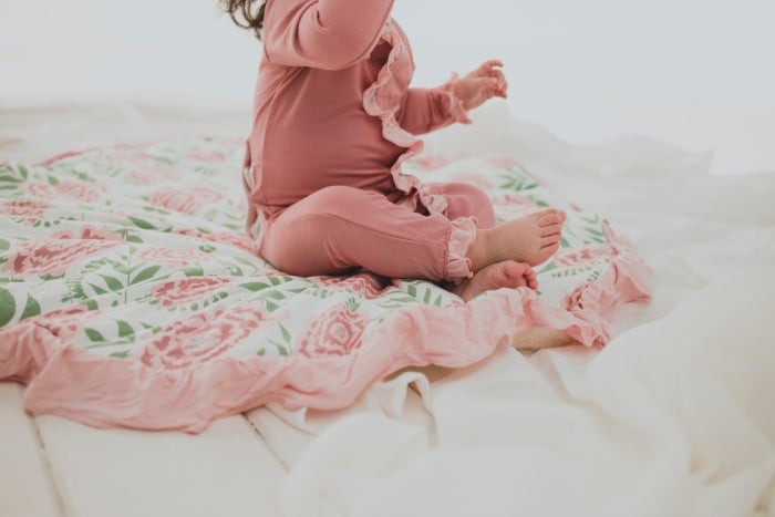 Close up image of baby blanket on floor with baby sitting on top