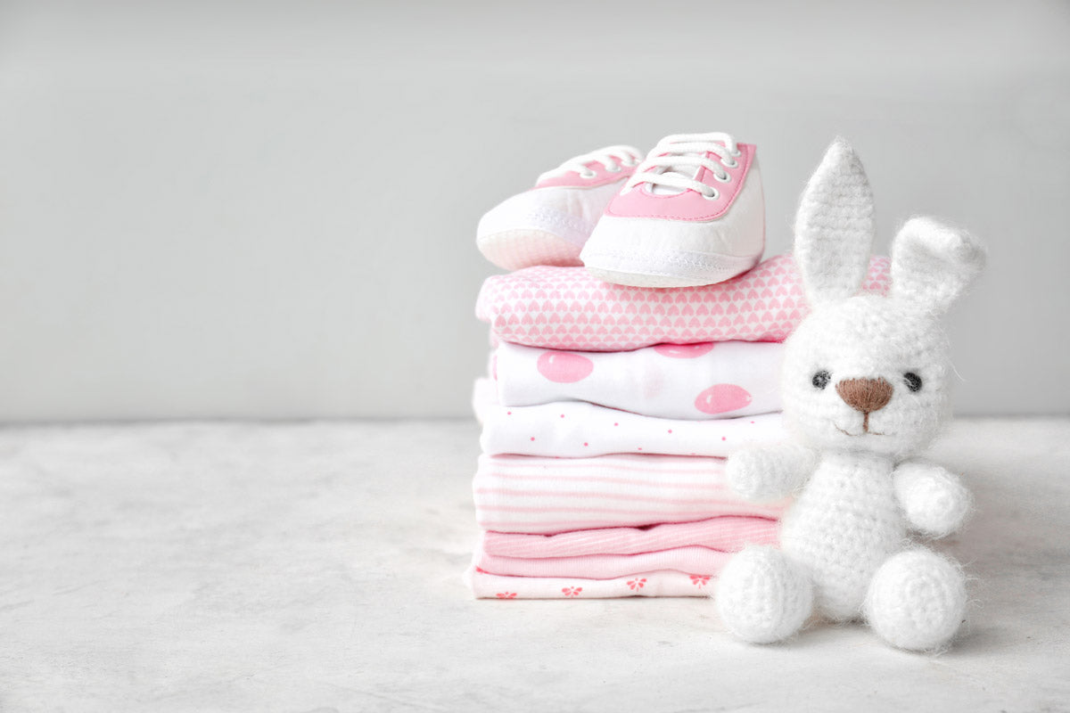 Folded baby clothing with a stuffed animal